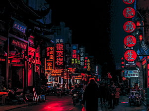 Neon-lit Chinese street at night with glowing red signs and pedestrians HD wallpaper