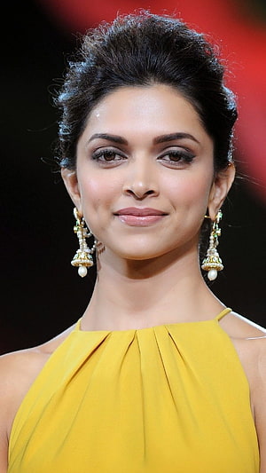 Deepika Padukone in a yellow halter gown with ornate pearl drop earrings at a red carpet event HD phone wallpaper