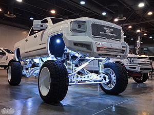White Custom Lifted Diesel Pickup Truck with Exposed Suspension at Indoor Auto Show HD wallpaper
