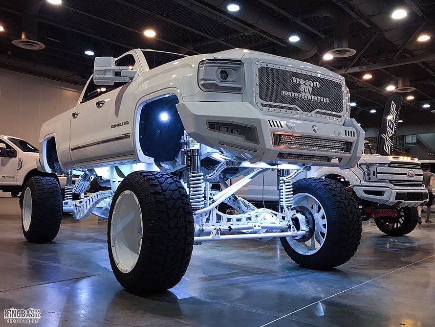 White Custom Lifted Diesel Pickup Truck with Exposed Suspension at Indoor Auto Show HD wallpaper