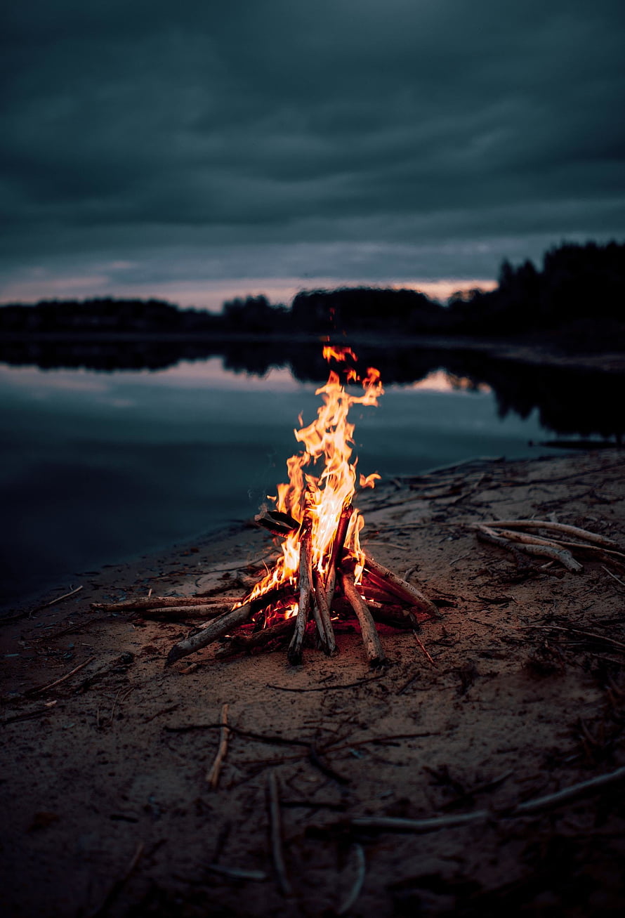Campfire Burning on a Sandy Lake Shore at Dusk with Dark Stormy Sky HD phone wallpaper