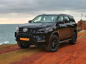 Black Toyota Fortuner SUV Parked on Coastal Cliff with Ocean View HD wallpaper