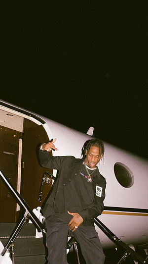 Travis Scott descending private jet stairs in black outfit at night HD phone wallpaper