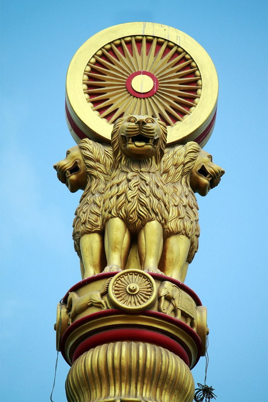 Golden Ashoka Pillar Capital with Lion Statues and Dharma Wheel Against Blue Sky HD phone wallpaper