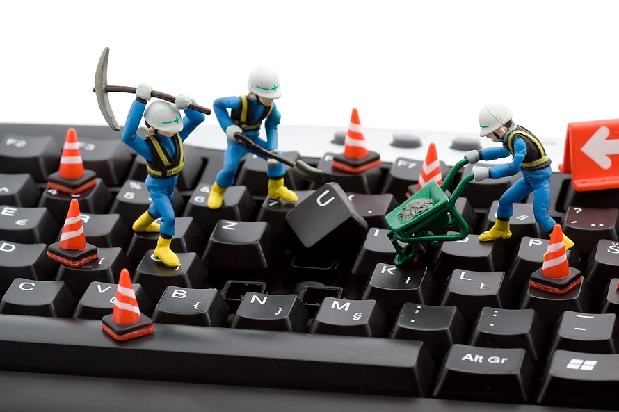Miniature construction workers repairing a black computer keyboard with tools and traffic cones HD wallpaper