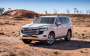 White Toyota Land Cruiser 300 VX parked in a dry desert landscape with red rock formations HD wallpaper