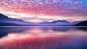 Vibrant Pink Clouds Reflecting on a Calm Mountain Lake at Dawn HD wallpaper