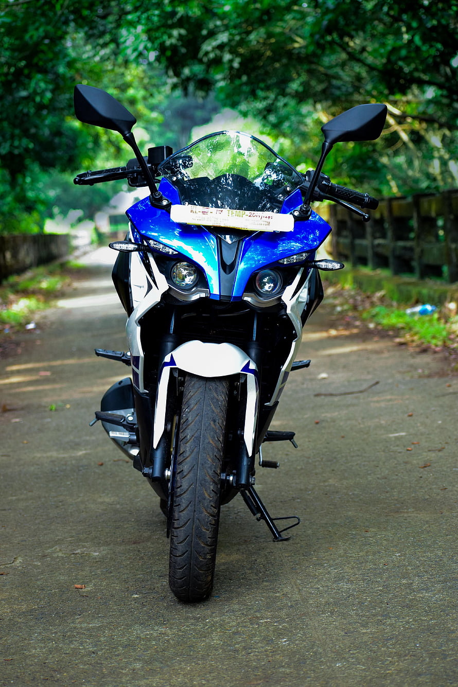 Bajaj Pulsar RS 200 Blue and White Sport Motorcycle Front View on a Forest Road HD phone wallpaper