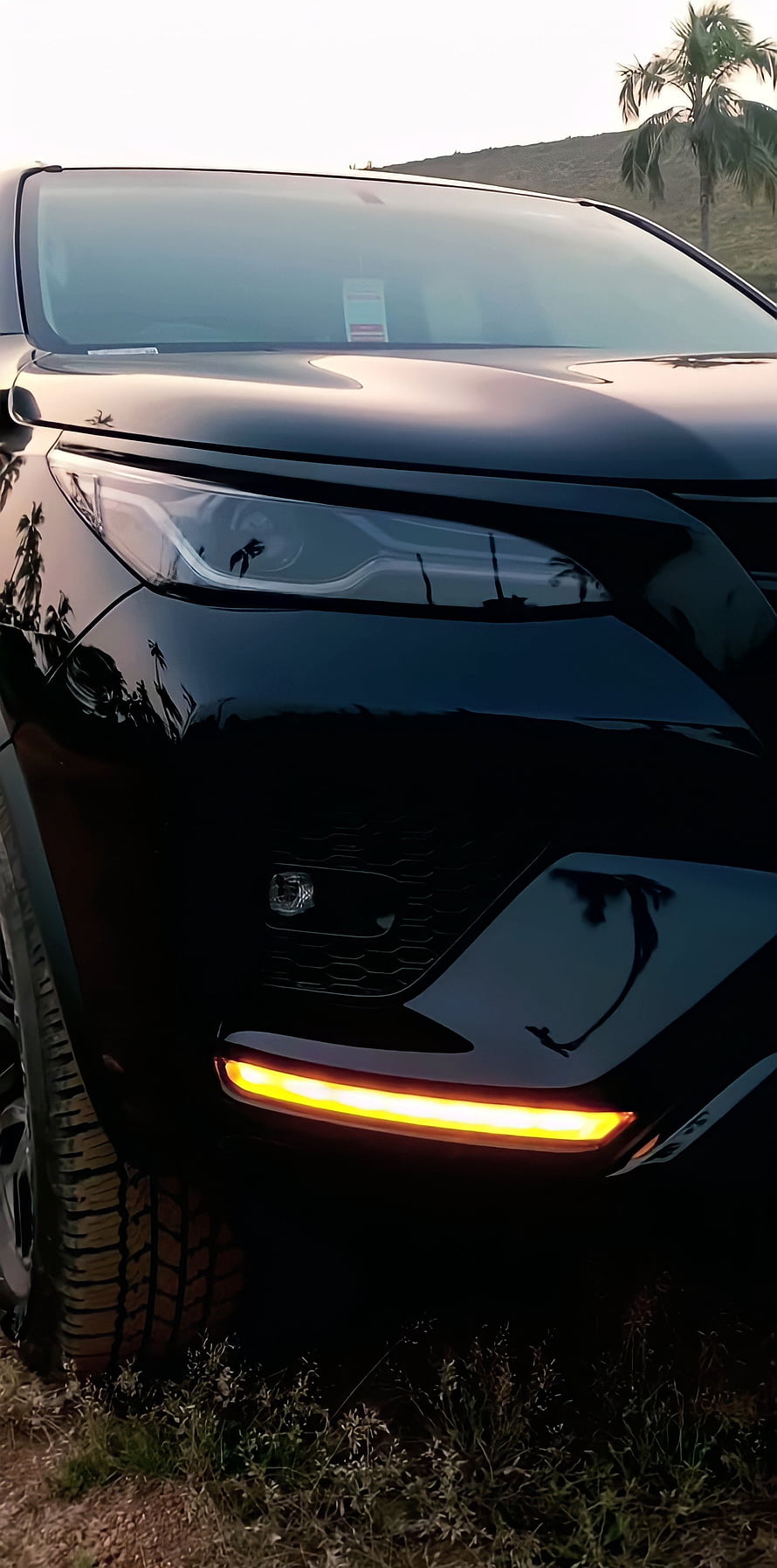 Close-up of a black SUV front corner with glowing amber turn signal and rugged tire HD phone wallpaper