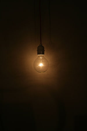 Vintage Edison Light Bulb Hanging in Dark Room with Warm Glow HD phone wallpaper