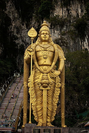 Golden Murugan Statue at Batu Caves with Staircase and Limestone Cliff Background HD phone wallpaper