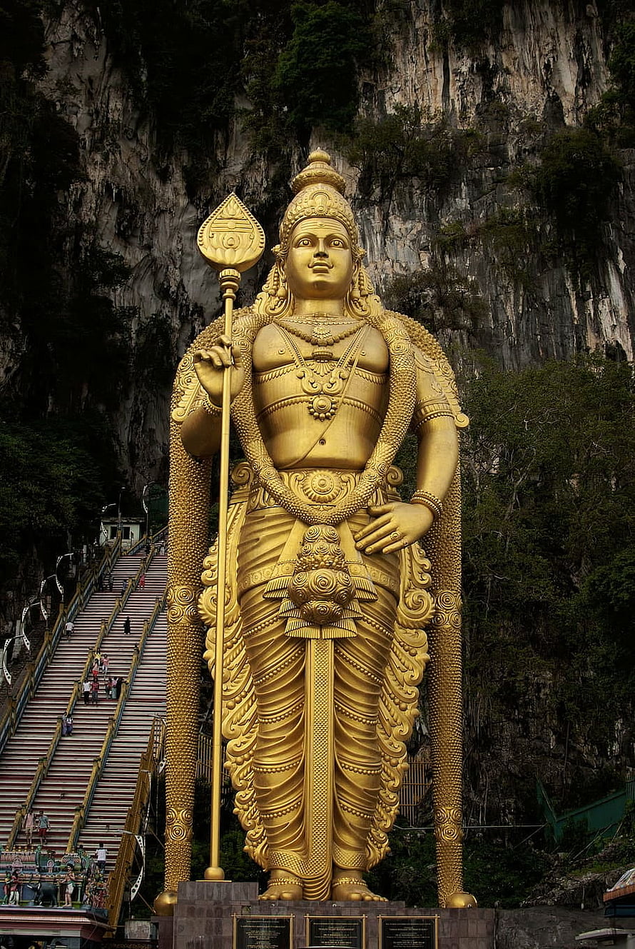 Golden Murugan Statue at Batu Caves with Staircase and Limestone Cliff Background HD phone wallpaper