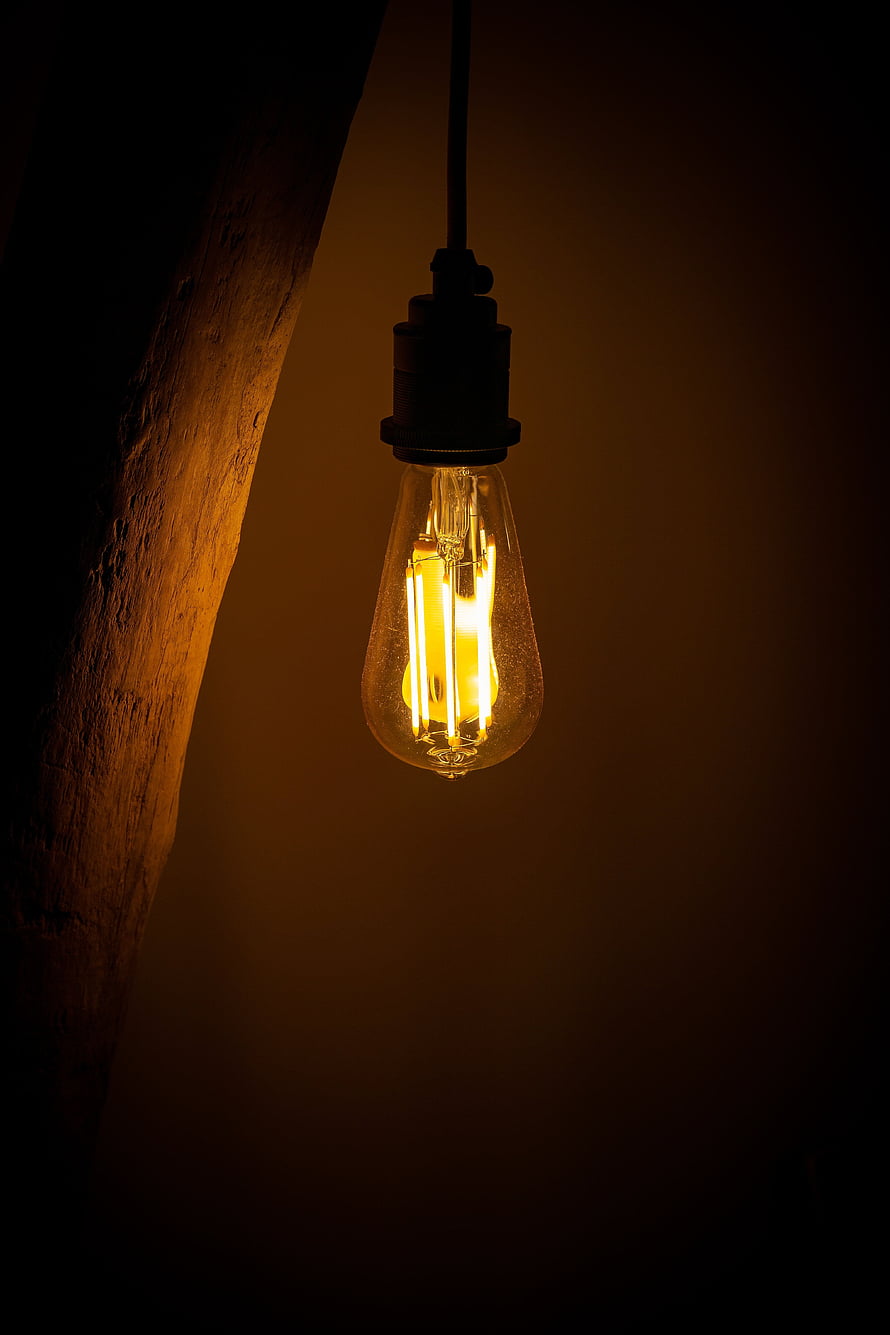 Vintage Edison Bulb Hanging in Dark Room with Warm Glow HD phone wallpaper