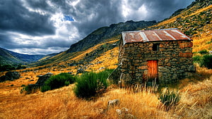 Rustic Stone Cabin in Golden Mountain Valley Under Stormy Sky HD wallpaper