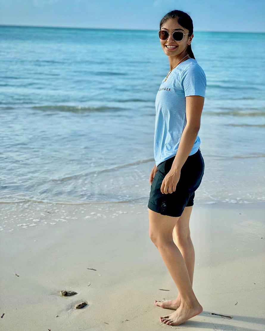 Harleen Deol in a light blue t-shirt and black shorts on a sunny beach HD phone wallpaper