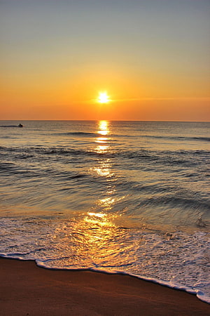 Golden sunrise over calm ocean waves with a distant boat on the horizon HD phone wallpaper