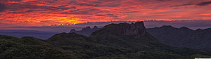 Dramatic Crimson Sunset Over Lush Mountain Ranges and Rocky Peaks HD wallpaper