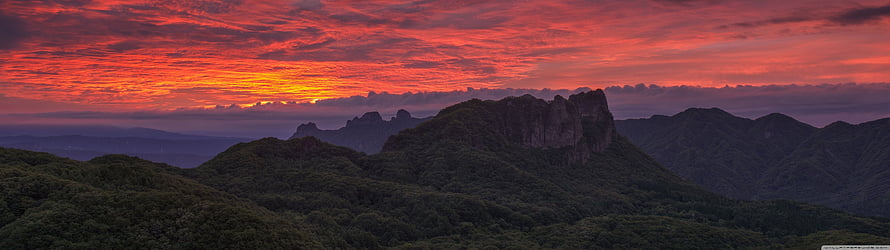 Dramatic Crimson Sunset Over Lush Mountain Ranges and Rocky Peaks HD wallpaper
