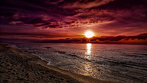 Dramatic Purple and Orange Sunset Over Ocean Beach with Cloudy Sky HD wallpaper
