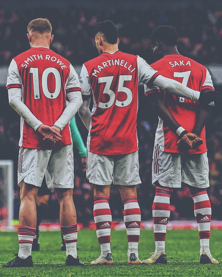 Arsenal trio Smith Rowe, Martinelli, and Saka standing together on the pitch in red home kits HD phone wallpaper