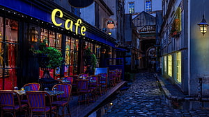 Moody European Cafe on a Rainy Cobblestone Alley at Night HD wallpaper