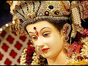 Close-up of a beautifully adorned Hindu goddess statue with intricate jewelry and floral garlands HD wallpaper