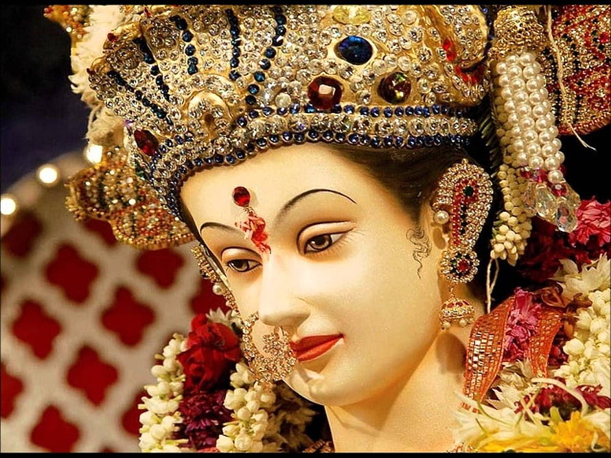 Close-up of a beautifully adorned Hindu goddess statue with intricate jewelry and floral garlands HD wallpaper