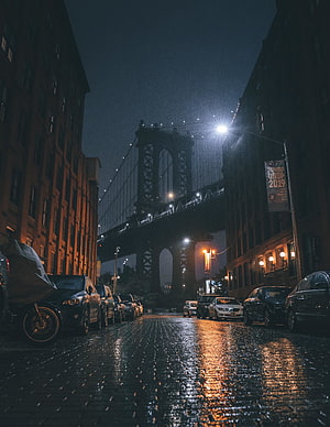 Moody Night View of the Manhattan Bridge Over a Wet Cobblestone Street in New York City HD phone wallpaper
