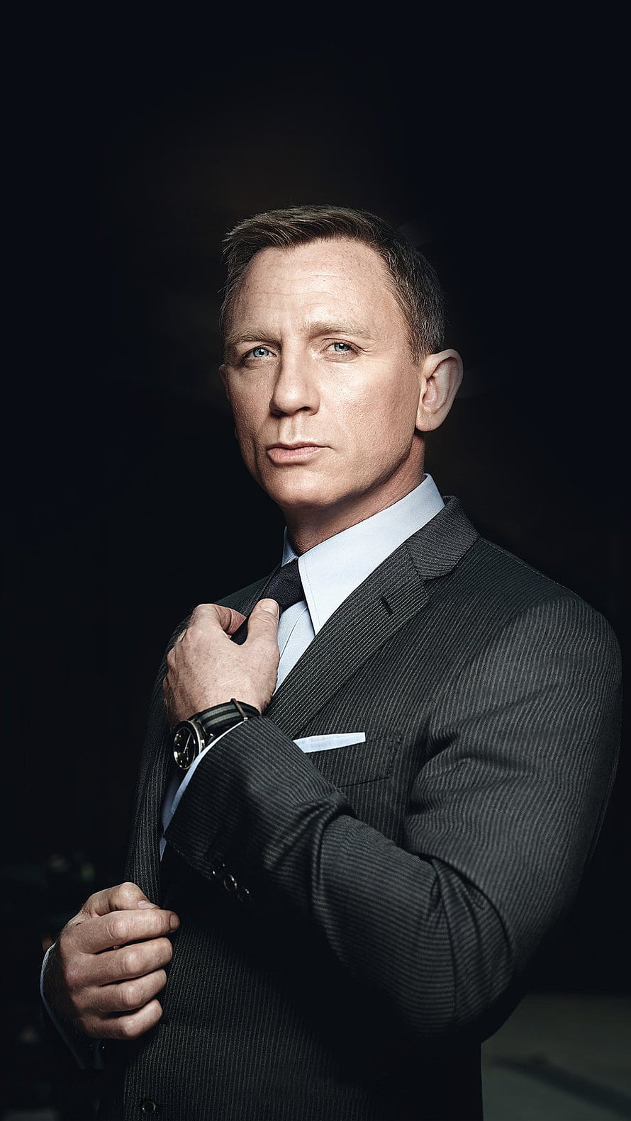 Daniel Craig as James Bond in a dark pinstripe suit adjusting his tie HD phone wallpaper