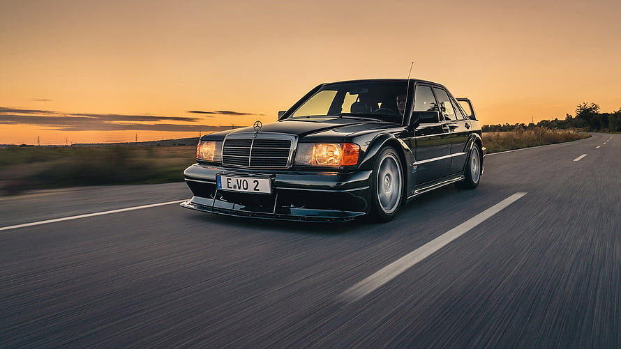 Black Mercedes-Benz 190 E 2.5-16 Evolution II driving on a highway at sunset HD wallpaper