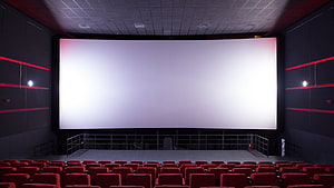 Empty Cinema Auditorium With Rows Of Red Seats Facing A Large White Projection Screen HD wallpaper