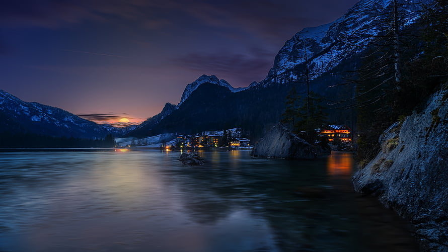 Alpine Lake at Dusk with Snow-Capped Mountains and Glowing Village Lights HD wallpaper