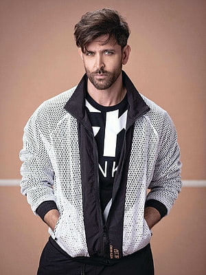 Hrithik Roshan wearing a white mesh jacket and black t-shirt posing against a beige background HD phone wallpaper