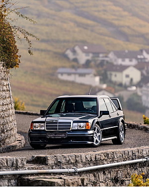 Black Mercedes-Benz 190E 2.5-16 Evolution II parked on a scenic stone-walled road HD phone wallpaper