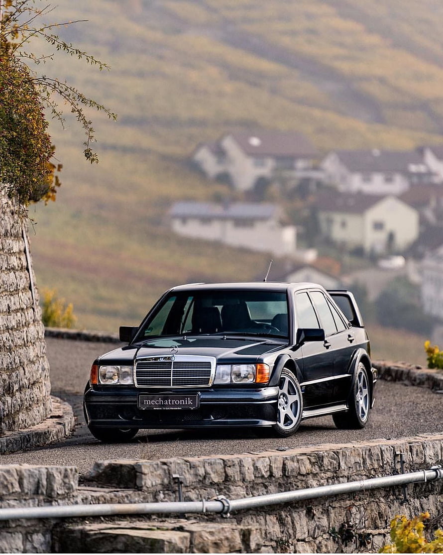 Black Mercedes-Benz 190E 2.5-16 Evolution II parked on a scenic stone-walled road HD phone wallpaper