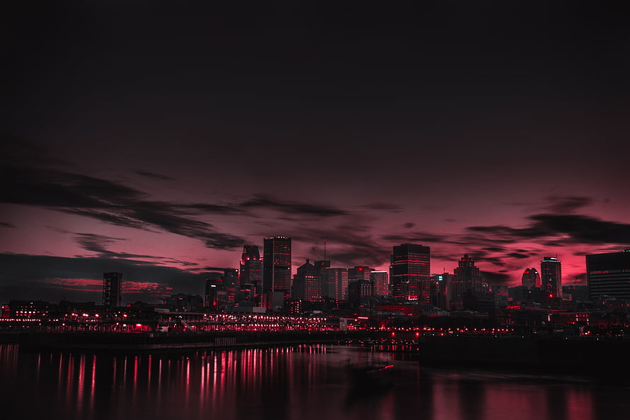 Dark Red City Skyline at Night with Dramatic Clouds and Water Reflections HD wallpaper