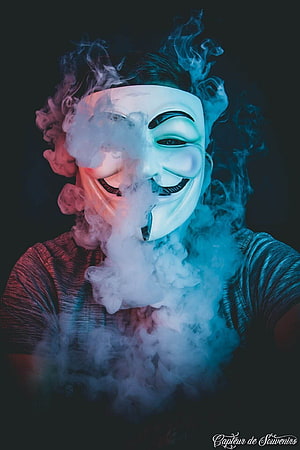 Person Wearing Guy Fawkes Mask Surrounded by Dramatic Smoke and Neon Lighting HD phone wallpaper