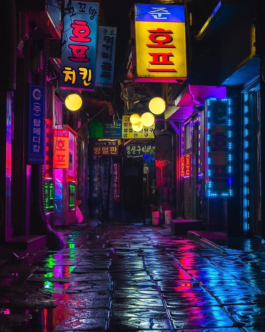 Neon-lit Korean alleyway at night with wet cobblestone street reflecting vibrant pink and blue lights HD phone wallpaper