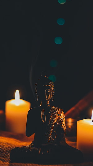 Serene Buddha Statue Silhouette Illuminated by Warm Candlelight in a Dark Meditation Setting HD phone wallpaper