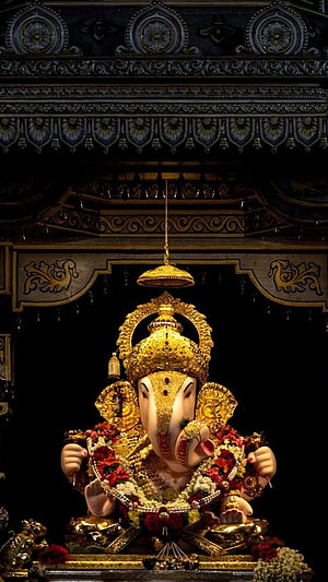 Golden Ganesha Idol Adorned with Flowers and Jewels in Temple Shrine HD phone wallpaper