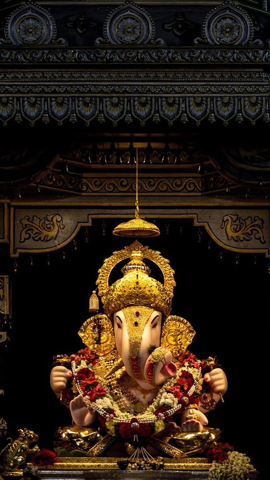 Golden Ganesha Idol Adorned with Flowers and Jewels in Temple Shrine HD phone wallpaper