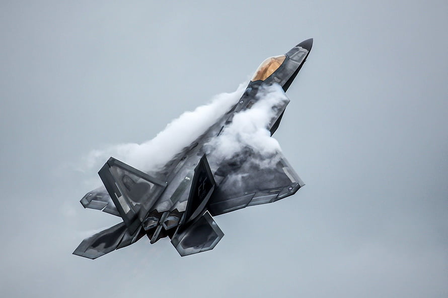 F-22 Raptor Stealth Fighter Jet Breaking Through Clouds in High Speed Flight HD wallpaper