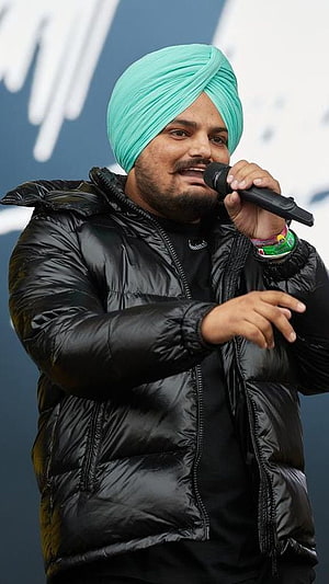Sidhu Moose Wala performing live on stage wearing a mint green turban and black puffer jacket HD phone wallpaper