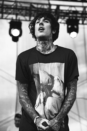 Black and white portrait of a tattooed male musician performing on stage with a microphone HD phone wallpaper