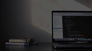 Minimalist Dark Workspace With Laptop Showing Code Editor And Stack Of Books HD wallpaper