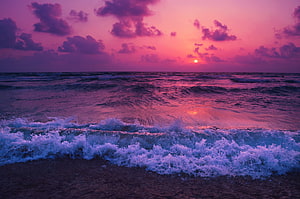 Vibrant Purple and Pink Sunset Over Ocean Waves Crashing on Sandy Beach HD wallpaper