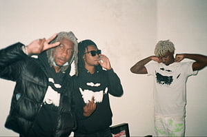 Ken Carson and friends posing in a casual indoor setting with streetwear fashion HD wallpaper