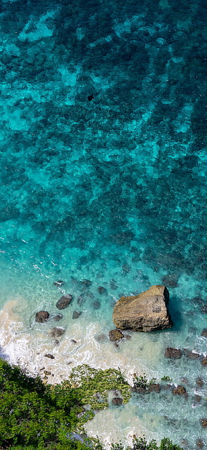 Aerial View of Turquoise Ocean Water, Rocky Shoreline, and Tropical Vegetation HD phone wallpaper