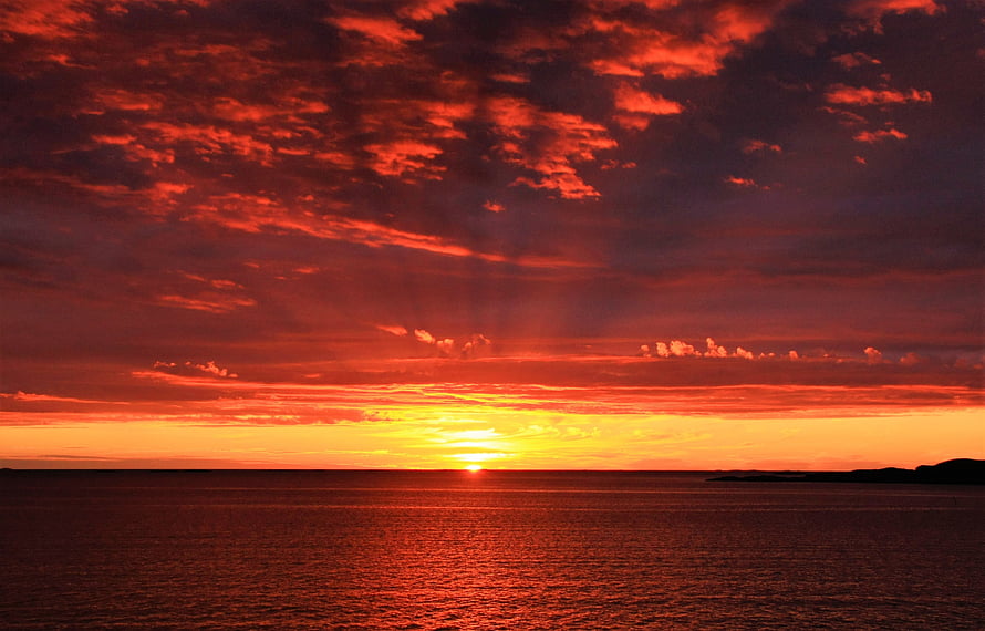 Vibrant Crimson Sunset Over Calm Ocean With Dramatic Clouds And Golden Horizon HD wallpaper