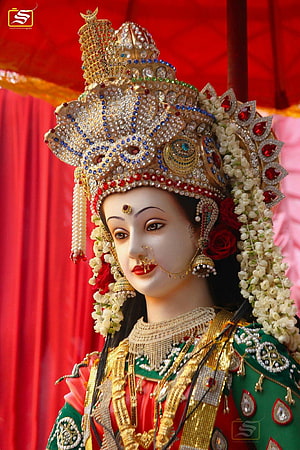 Ornate Goddess Statue with Golden Crown and Floral Garlands HD phone wallpaper